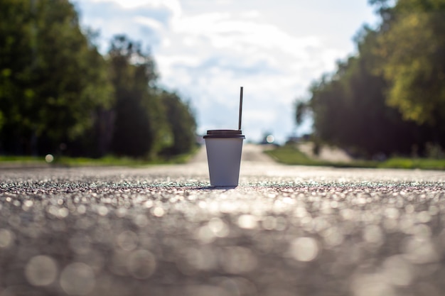 Photo a white paper cup with a lid and a tube stands on the road to the city.