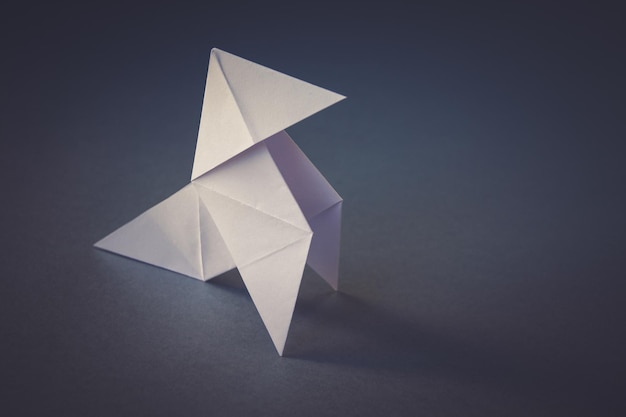 White paper hen origami isolated on a grey background