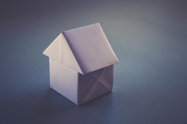 White paper house origami isolated on a grey background