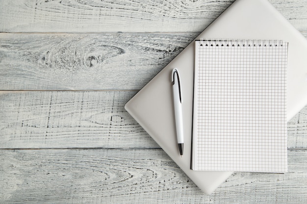 White paper Notepad and laptop on vintage shabby white wooden background. the view from the top. flat lay