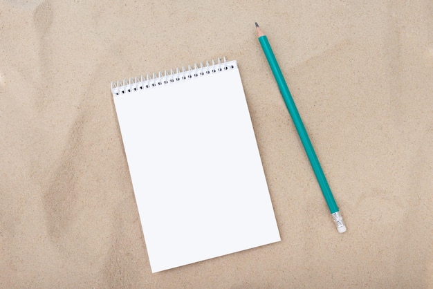 White paper and pencil on sandy background layout template