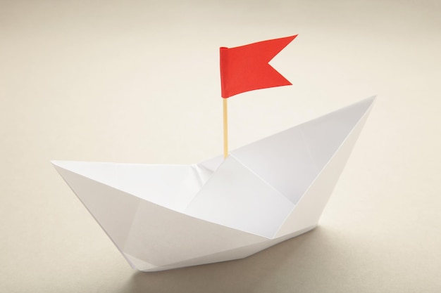 White paper ships and red flags on grey background