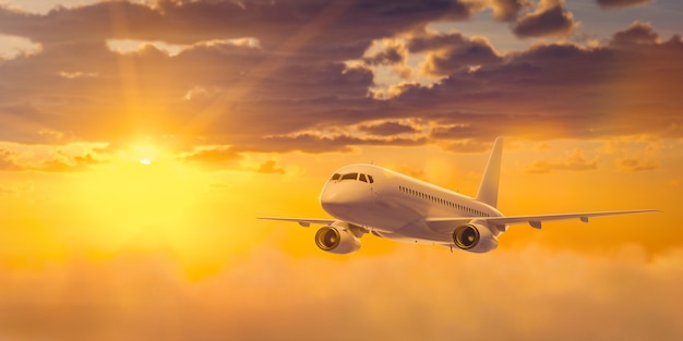 White passenger airplane is flying in the sky with multicolored clouds at sunset