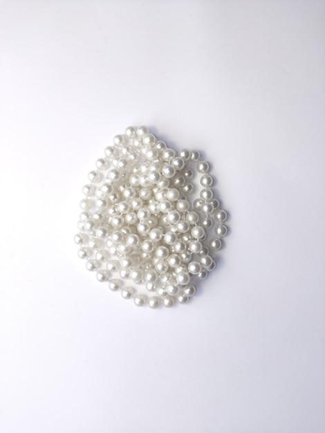 White pearl beads lie on a white background isolated