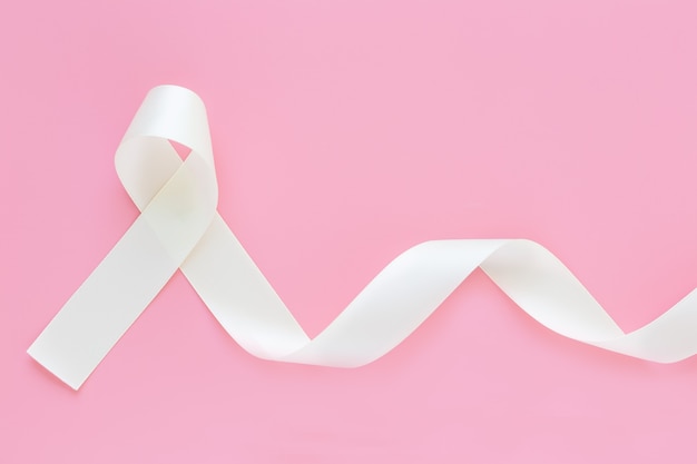 White pearl ribbon curl on pink isolated background with copy space.