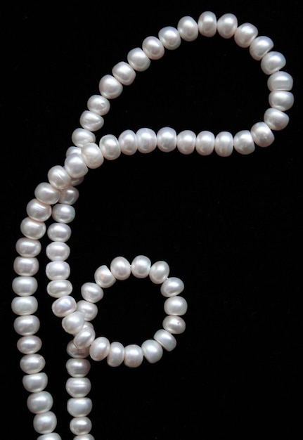 White pearls on the black silk as background