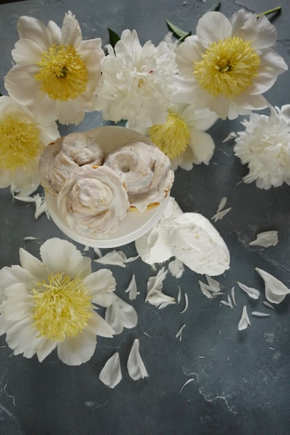 white peonies and vanilla meringue cakes on blue  Delicate wedding background Top view