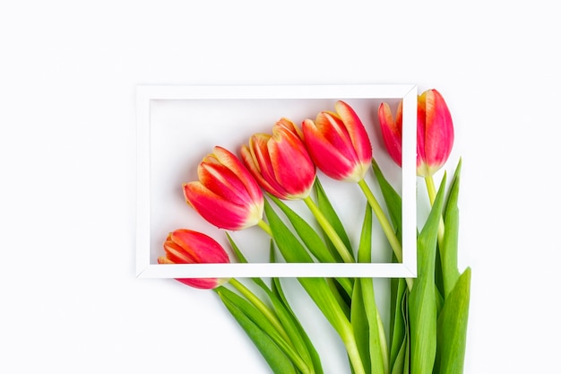 White photo frame decorated with red tulips flowers.