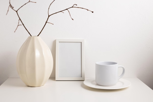 Photo white photo frame with vase and cup with saucer