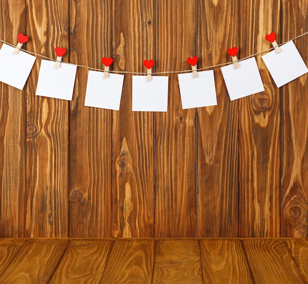 White pieces of paper on clothespins with a heart on a wooden background