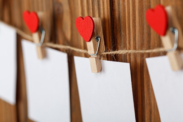 White pieces of paper on clothespins with a heart on a wooden background