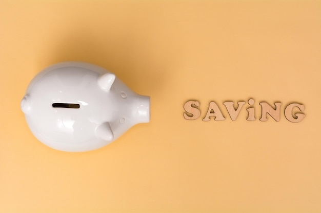 White piggy bank and beige background View from above Saving concept