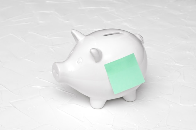 White piggy bank and green sticker on a white background. Saving concept.