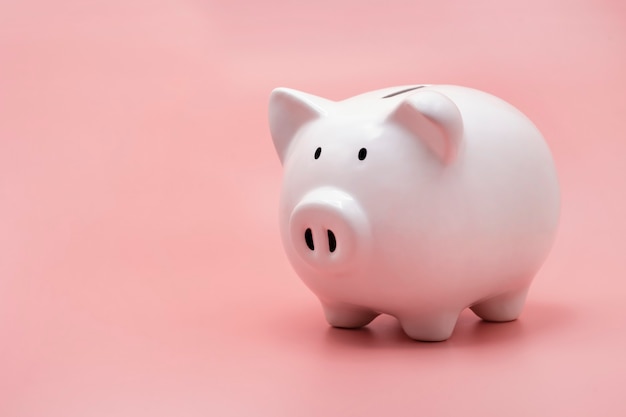 White piggy bank for money saving isolated on pastel pink background with copy space.