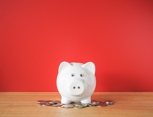 White Piggybank and money coin on wooden desk