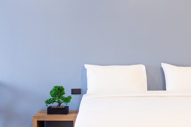 white pillow on bed decoration with light lamp and green tree in flowerpots