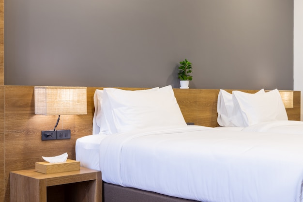 white pillow on bed decoration with light lamp and tissue box in hotel bedroom interior