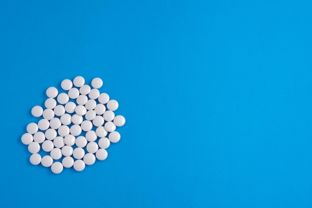 White pills are scattered on a blue background