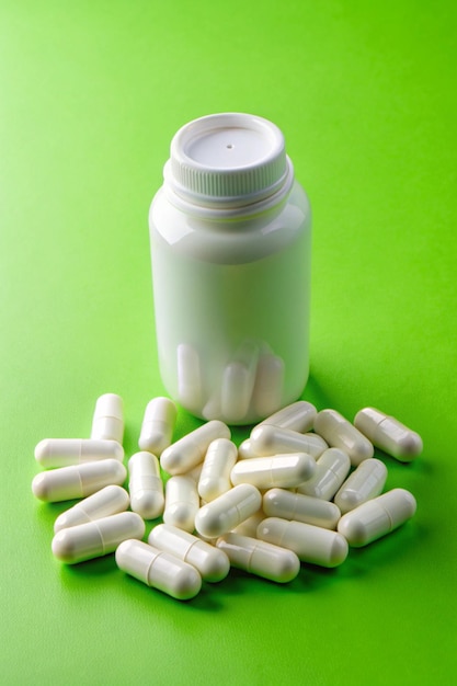 Photo white pills and bottle on green background medical pharmacy concept probiotics benefits