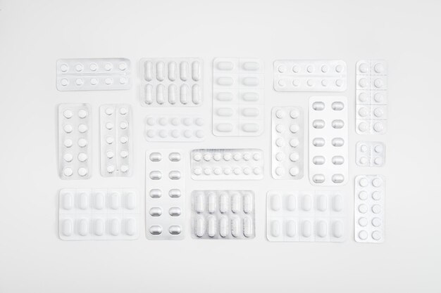 White pills and capsule medicine tablet in foil blister pack with on white background minimalistic