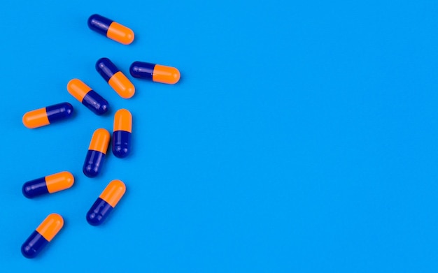 White pills in capsules on a blue background copy space