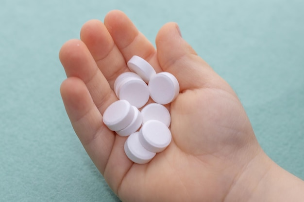 Photo white pills in a cute little kids hand mothers hand is holding childs one medicine round table