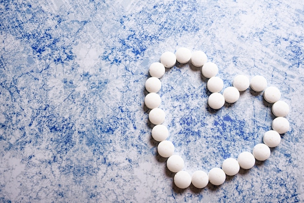 white pills from heart on blue background. accept gifts or love or romance or cardiology concept.