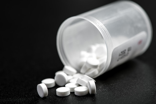 White pills spilling out of a bright pill bottle