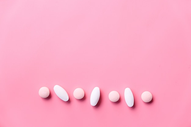 white pills spilling on pink space with copy space