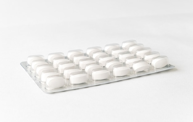 White pills tablets in package on a white