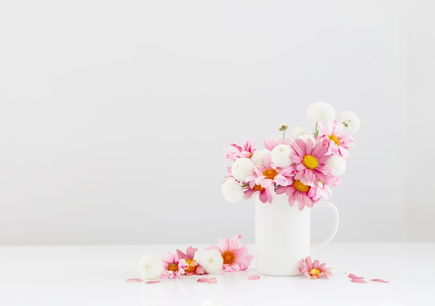 white and pink chrysanthemums in white cup on white background