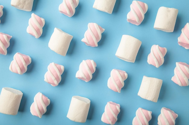 Photo white and pink marshmallow on blue background. pastel creative textured pattern. minimal. top view