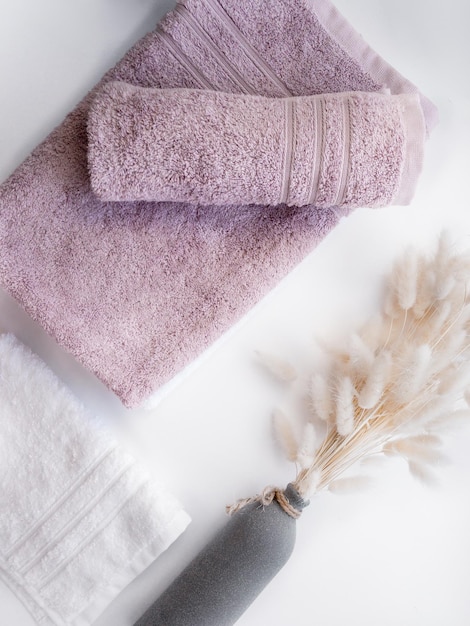 White and pink twisted towels with dried flowers on the white background