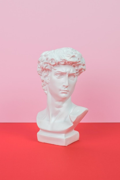 White plaster statuette on a red and pink background Minimal concept