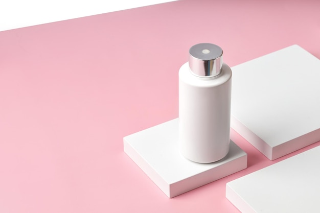 White plastic Bottle of cream with a dispenser on square podium and pink background Mock up