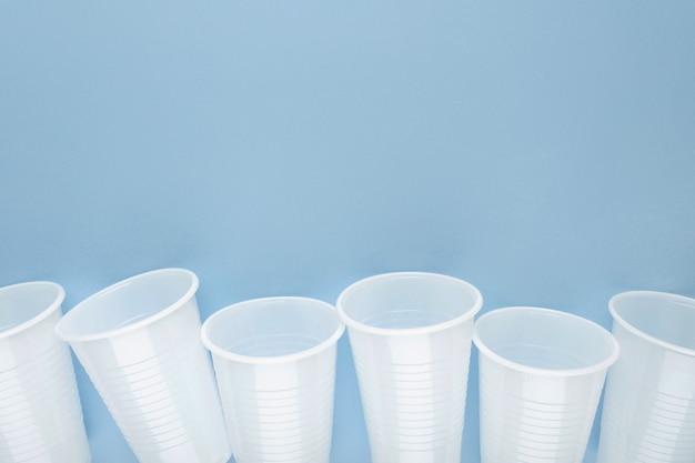 White plastic empty cups laid out in a row. Ecological problem concept.