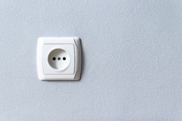 White plastic euro socket on gray wall with copyspace