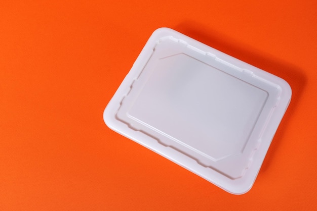 White plastic fast food box on orange background - side view, isolate