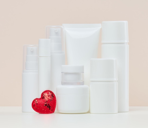 White plastic jars and tubes for liquid cosmetics on a beige background Branding advertising