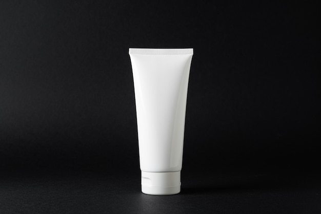 White plastic tube of cream moisturizer on a black background