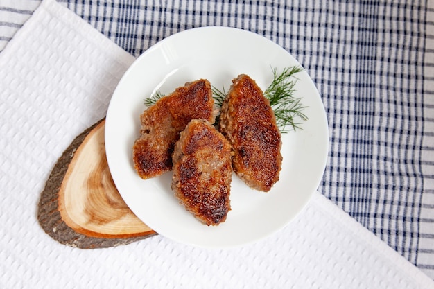 White plate with beef cutlets laying on traditional cheched kitchen towel