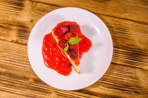 White plate with cheesecake New York leaf of mint and raspberries on wooden table Top view