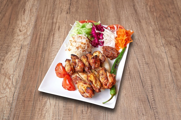 White plate with Chicken drumsticks and vegetables on wooden table