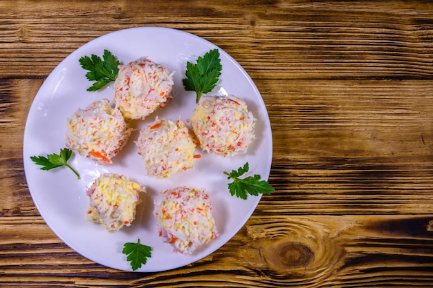 White plate with crab-cheese balls on rustic wooden table. Top view