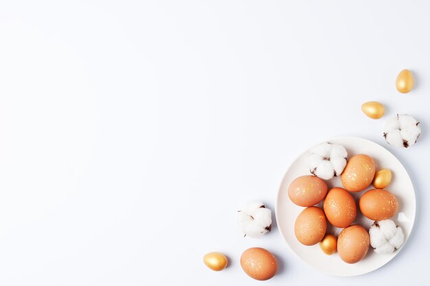 Photo white plate with easter eggs and flowers on white background flat lay copy space