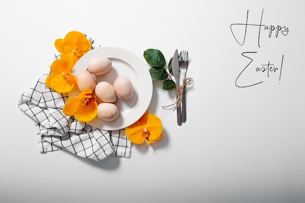 White plate with eggs on white background Happy Easter card with plate with eggs flowers and green leaves