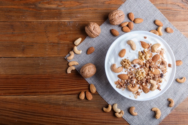 White plate with greek yogurt, granola, almond, cashew, walnuts