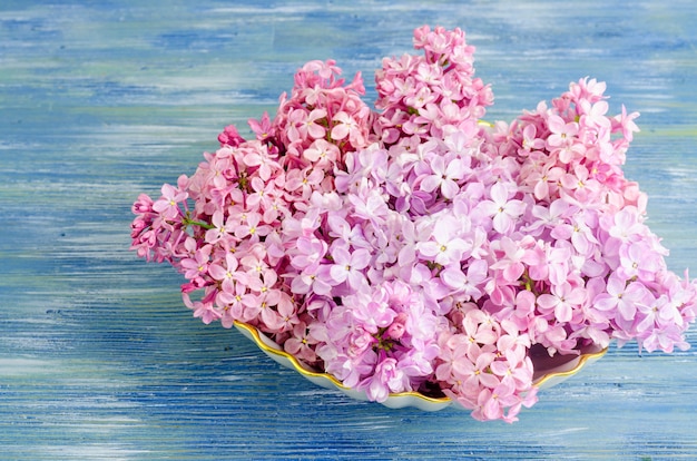 White plate with lilac flowers on table.