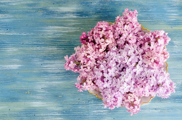 White plate with lilac flowers on table.