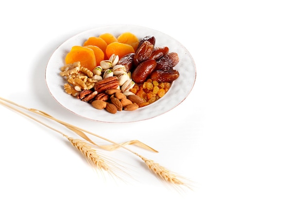 White plate with a mix of nuts and dried fruits ears of wheat symbol the Jewish holiday Tu Bishvat Top view